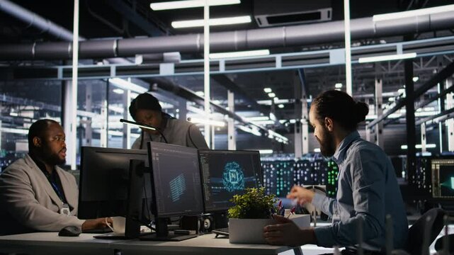 Furious data center engineer packs desk belongings after being replaced by AI automation handling operations. Frustrated man suffering from workforce displacement by artificial intelligence, camera A