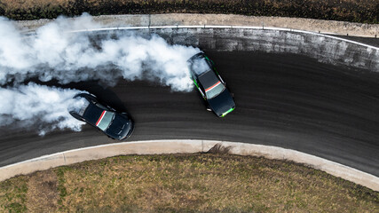 Aerial view high speed drift battle car, Two drift cars drifting battle on race track with lot of smoke, Twin drift car drifting battle, Professional driver drifting car battle high speed and smoke. © Kalyakan