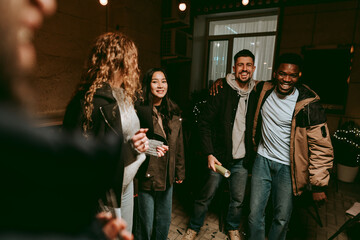 Group of friends enjoying a joyful evening gathering indoors at a cozy location with soft lighting...