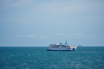 Ferry Vessel Navigating Calm Ocean Waters Under Clear Blue Sky with Distant Horizon
