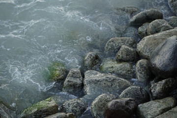 Gentle Waves Lapping Against Smooth Rocks at the Shoreline of a Coastal Ocean