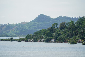 Tranquil River Landscape with Lush Greenery and Mountainous Background in Tropical Region