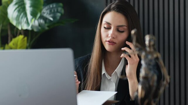 Peaceful negotiations, finding a compromise with the other side, online counseling. A businesswoman lawyer talking on the phone at her laptop.  The concept of justice and law.
