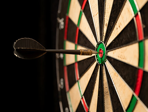 Dart hits bullseye on dartboard in dark