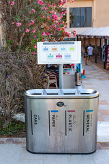 A four-part recycling bin station labeled in English and Arabic, with a sign promoting...
