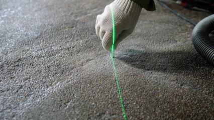 Construction worker using green laser level on concrete floor