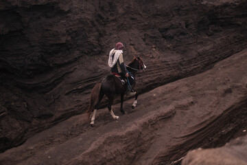 view of a person on horseback in a rocky, volcanic environment. Java, Indonesia - 19th March 2025