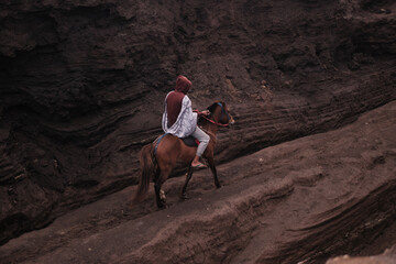 view of a person on horseback in a rocky, volcanic environment. Java, Indonesia - 19th March 2025