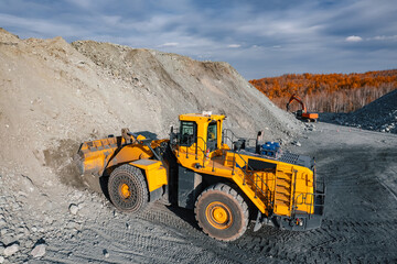 Aerial photo mining large yellow backhoe loader holds full bucket of gold and copper ore at open pit mine