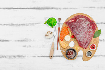 Gourmet food concept with raw flank steak, assorted spices, sauces, and herbs arranged creatively