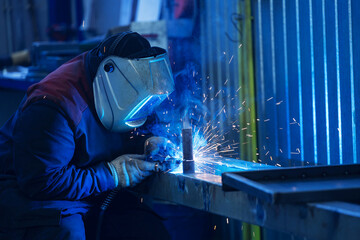 Welder working in industrial factory with sparks flying