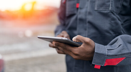 African male surveying engineer in sand quarry using tablet for ore mining operations, concept...