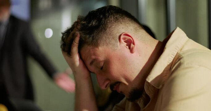 Man clutching head in distress after confrontation in modern office, experiencing emotional breakdown, conflict, anxiety, stress, and workplace tension