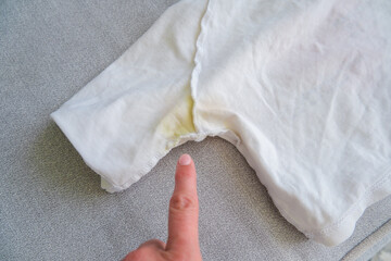 A yellow spot on a white T-shirt. Top view.
