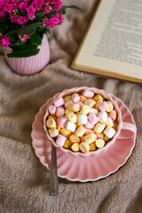 Cozy Coffee and Marshmallows with a Book. A warm cup of coffee with colorful marshmallows, a book, and a soft blanket for a perfect cozy moment