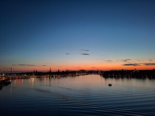 A serene sunset scene with a city skyline reflecting over tranquil water, radiating peace and...