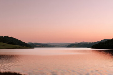 Obraz premium serene summer dawn at tranquil lake sky painted in soft pastels as sun rises