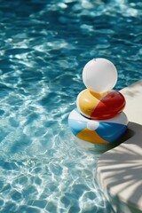 Obraz premium A pool with a yellow and red beach ball on top of a blue and yellow beach ball. The pool is blue and the beach balls are bright and colorful
