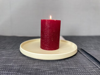 Large burning red candle on a plate