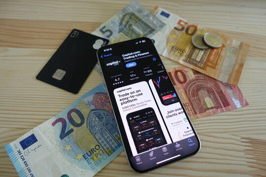 Kiel, Germany - 05-21-2025: Capitalcom Finance App Displayed in Apple App Store Alongside Euro Currency and Debit Card