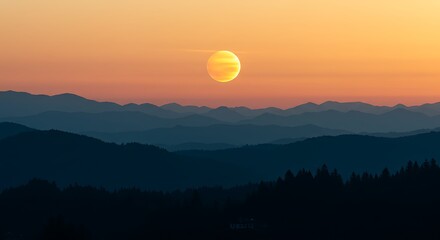 Fototapeta premium A vibrant orange sun descends over rolling layers of blue mountains and forested hills, creating a serene and breathtaking natural landscape.