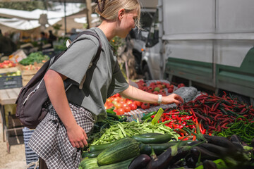 Young woman choosing fresh organic vegetables at a local market. Concept of eco lifestyle,...