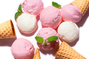 Strawberry and vanilla ice cream scoops and waffle cones close up