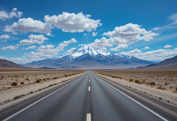 Naklejka premium Endless open highway leading to snow capped mountains under a bright blue sky with scattered clouds