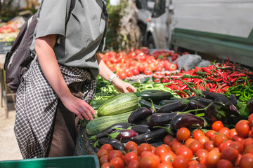 Young woman choosing fresh organic vegetables at a local market. Concept of eco lifestyle,...