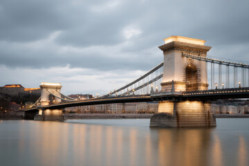 Fototapeta premium serene view of chain bridge in budapest at dusk illuminated by soft warm lights