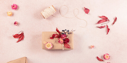 Autumn creative holiday present. Handmade paper gift box with foliage dried leaves on light table....