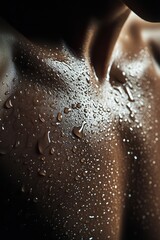 Fototapeta premium Close-up of a glistening muscular chest with droplets of water highlighting skin texture in soft lighting
