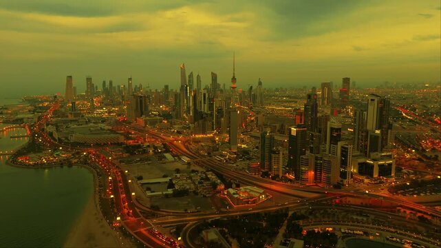 4K drone view of Kuwait City during golden hour. Illuminated skyline, glowing roads, and dramatic clouds. Perfect for documentaries, travel content, or city B-roll.