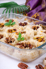Kunafa dessert made of kataifi dough with pistachio and pecan nuts served in the glass dish. Egyptian cuisine