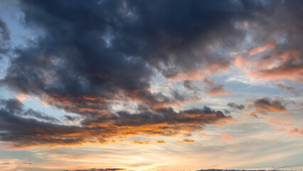 Morning light filters through layered clouds, blending warm golden and soft pink hues, while the shifting sky creates a dynamic contrast between shadow and illumination