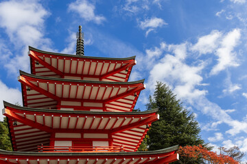Chureito Pagoda stand against a bright blue sky with scattered clouds, showcasing the symmetry and vivid red details of this historic landmark in Fujiyoshida