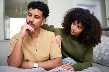 Worried Couple Sitting Together on Couch Sharing Emotions
