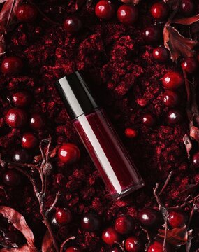 Dunkles, burgunderfarbenes Kosmetikprodukt inmitten von roten Beeren