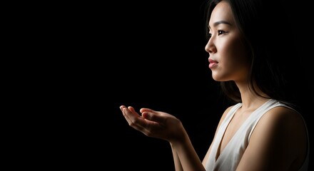 Asian Woman Offering Hands Upward in Dark Studio Profile Shot