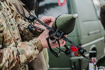 Person military in camouflage adjusting a custom FPV drone with an attached training munition