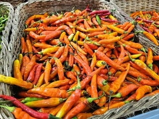 Assortment of red and orange chilies in basket, perfect for spicy food, cooking, flavor, spice-related visuals, agriculture, or market themes