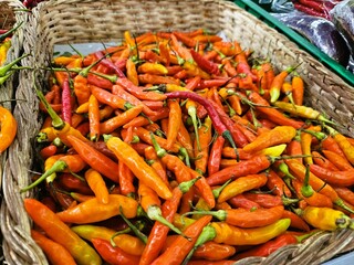 Assortment of red and orange chilies in basket, perfect for spicy food, cooking, flavor, spice-related visuals, agriculture, or market themes