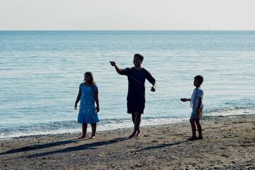 A father tries to launch a kite while his daughter and young son join him at the beach during a...