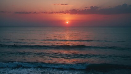 Obraz premium Sunset over the ocean with calm waves and colorful sky.