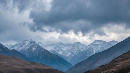Fototapeta premium Snow-capped mountains under cloudy sky with valleys, scenic landscape.