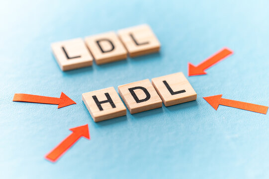 Concept of difference between HDL and LDL cholesterol, with terms composed with wooden alphabet on a blue background, good cholesterol HDL.
