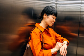 Businesswoman checks watch in elevator during a busy workday in a modern office building