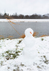 funny snowman on background river on  cloudy day