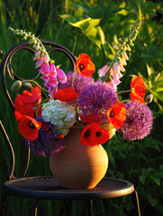 Bright flowers in a clay pot on a chair in a lush garden at sunset