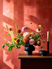 Beautiful floral arrangement on a wooden table against a vibrant red wall at sunset